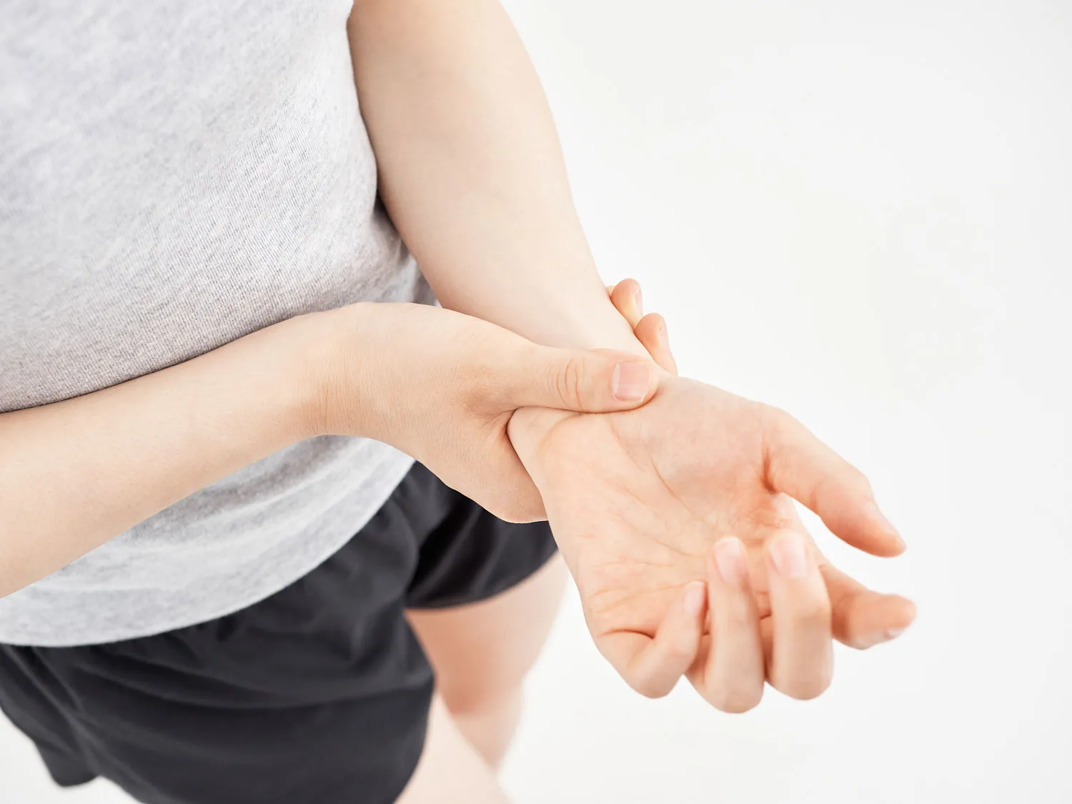 a woman pressing her aching wrist against a white 2023 11 27 04 54 43 utc